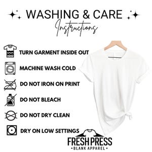 Puede incluir: Una camiseta blanca cuelga de una percha de madera, con instrucciones de lavado a la izquierda. Las instrucciones incluyen voltear la prenda, lavar a m&aacute;quina con agua fr&iacute;a y evitar planchar sobre la impresi&oacute;n, usar lej&iacute;a y limpiar en seco. El logotipo de la marca "FRESH PRESS *BLANK APPAREL*" est&aacute; en la parte inferior.