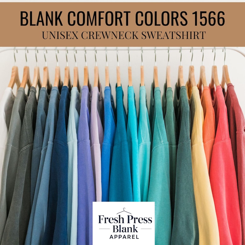 May include: A selection of unisex crewneck sweatshirts in a spectrum of colours, displayed on wooden hangers. The sweatshirts vary from grey to red hues. The image includes the text "BLANK COMFORT COLORS 1566" and "UNISEX CREWNECK SWEATSHIRT". The Fresh Press Blank Apparel logo is visible.