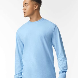 May include: A light blue long-sleeve t-shirt. The shirt has a crew neck and long sleeves with ribbed cuffs. The fabric appears to be a soft, solid color. The shirt is a casual style.