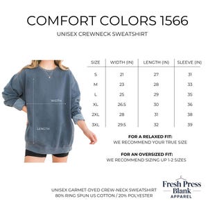 May include: A faded blue unisex crewneck sweatshirt. The image includes a size chart with measurements in inches for width, length, and sleeve length. The text "COMFORT COLORS 1566" is at the top of the image.