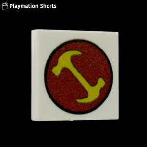 May include: A white square tile with a red circle featuring a yellow hammer icon. The tile has a black border around the red circle. The text "Playmation Shorts" is in the top left corner.