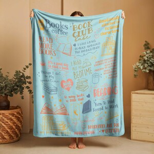May include: A light blue blanket with various book-themed illustrations and text. The blanket features phrases like "Books & coffee," "Read more books," and "Book Club Babe." The design includes images of books, hearts, and a bookstore.