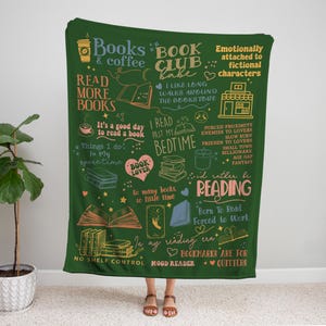 May include: A dark green throw blanket with book-themed illustrations and text. The blanket features phrases like "Read More Books," "Book Club Babe," and "I'd rather be reading." It includes drawings of books, coffee cups, and hearts.