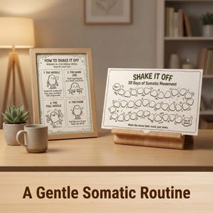May include: A framed print with the text "HOW TO SHAKE IT OFF" and illustrations of stress-relieving movements. Beside it, a card titled "SHAKE IT OFF" with a 30-day somatic movement chart. A mug and a small plant are also on the table.