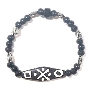 May include: Black beaded bracelet with a silver charm and a black and white patterned wooden bead.