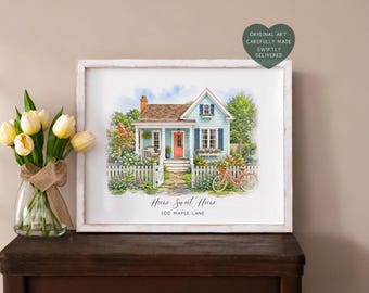 May include: A framed watercolour print of a light blue house with a coral front door, a white picket fence, and a red bicycle in the front garden. The text reads Home Sweet Home and 100 Maple Lane. A heart-shaped sticker says Original Art.