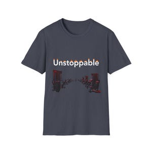 Puede incluir: Camiseta gris oscuro con la palabra "Unstoppable" en blanco con detalles de llamas. La camiseta presenta un gráfico de sillas rojas en fila, creando un tema motivacional.