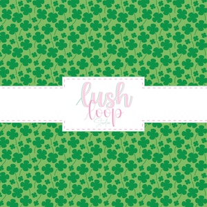 May include: Green background with a pattern of dark green shamrocks. A white rectangle with the text "lush loop Studio" in pink and light blue script is centered on the image.
