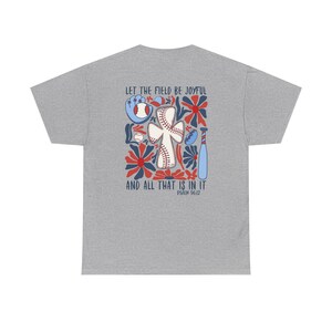 May include: A grey t-shirt with a baseball-themed design. The graphic includes a baseball, glove, bat, and flowers in red, blue, and white, with the text "LET THE FIELD BE JOYFUL AND ALL THAT IS IN IT" and Psalm 96:12.