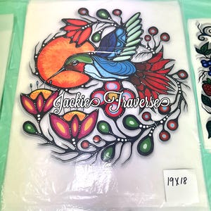 May include: A colorful artwork featuring a hummingbird with blue, red, and green feathers, surrounded by flowers and foliage. The artwork includes the text "Jackie Traverse" and measures 19 x 18 inches.