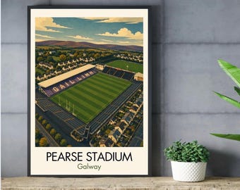 May include: A framed art print featuring an aerial illustration of Pearse Stadium in Galway, Ireland. The stadium has a green field with the text GAIL LIMH visible in the stands. The surrounding area includes houses, trees, and hills under a blue sky.