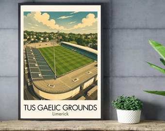 May include: A framed art print featuring an aerial illustration of TUS Gaelic Grounds in Limerick. The image depicts a green sports field surrounded by stadium seating, floodlights, and a residential landscape under a blue sky with white clouds.