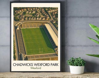 May include: A framed print featuring an aerial view of Chadwicks Wexford Park stadium with a green field, surrounding seating areas, and nearby residential houses. The text CHADWICKS WEXFORD PARK Wexford is printed in black at the bottom of the print.