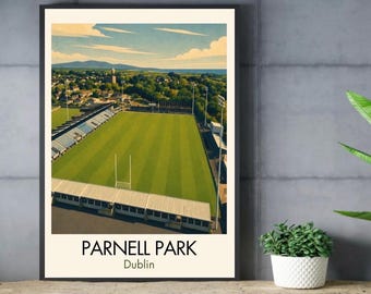 May include: A framed art print featuring an aerial view of Parnell Park in Dublin, showing a green sports field with white goalposts, stadium seating, and surrounding trees under a blue sky. The text Parnell Park Dublin is printed at the bottom.