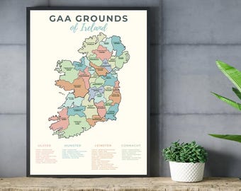 May include: A framed wall art print titled GAA Grounds of Ireland featuring a map of Ireland divided into counties with pastel colours. The map includes text labels for each county and lists of grounds categorised by the provinces of Ulster, Munster, Leinster, and Connacht.