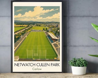May include: A framed art print featuring an aerial view of Netwatch Cullen Park in Carlow, Ireland. The illustration depicts a bright green sports field with white goalposts, surrounded by stadium seating, trees, and a blue sky with clouds.