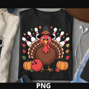 May include: Black t-shirt featuring a cartoon turkey wearing a pilgrim hat, with bowling pins as feathers. A red bowling ball and two pumpkins are at the bottom. Colorful autumn leaves are scattered around the turkey.
