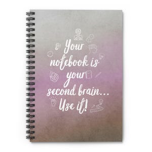 Puede incluir: Cuaderno de espiral con un fondo degradado gris, morado y marrón. La portada presenta el texto blanco "Your notebook is your second brain... Use it!" y dibujos relacionados con el cerebro.