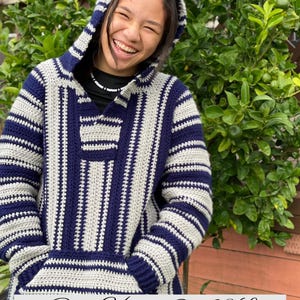 May include: A blue, grey, and white striped Baja hoodie with a hood and front pocket. The hoodie has a relaxed fit and is made of a soft, knitted material. The text "Baja Hoodie S - 3XL" is displayed at the bottom of the image.
