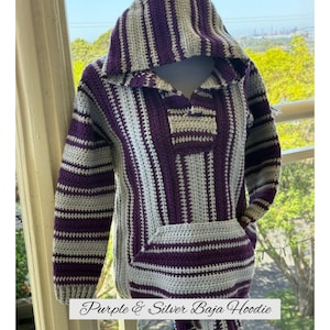 May include: A purple and silver Baja hoodie with a hood and a front pocket. The hoodie is made of a crocheted material with alternating stripes of purple and silver. The text "Purple & Silver Baja Hoodie" is at the bottom.