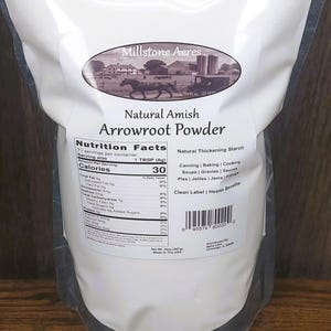 May include: A white bag of Millstone Acres Natural Amish Arrowroot Powder. The bag features a nutrition facts label and a graphic of a horse-drawn carriage. The text on the bag indicates it is a natural thickening starch.
