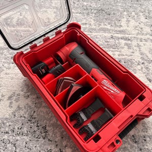 May include: A red Milwaukee FUEL power tool kit with a clear lid. The kit contains a multi-tool, batteries, and various attachments. The multi-tool is black and red. The case is open, revealing the tools inside.