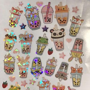 May include: A sheet of holographic stickers featuring various cartoon bubble tea designs. The stickers include animal-themed cups with panda, fox, cat, and bunny faces, along with star and heart-shaped accents. The bubble tea drinks are in various colors.