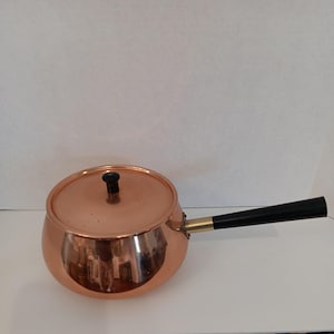 May include: A white ceramic mug with a black handle and the text "But First, Coffee" in a black, handwritten-style font. The mug is on a white surface.