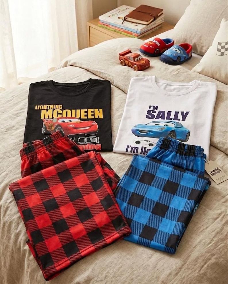 May include: Two sets of pajamas featuring Disney Cars characters. One set includes a black t-shirt with Lightning McQueen and red plaid pants. The other set features a white t-shirt with Sally and blue plaid pants, accompanied by matching character slippers.