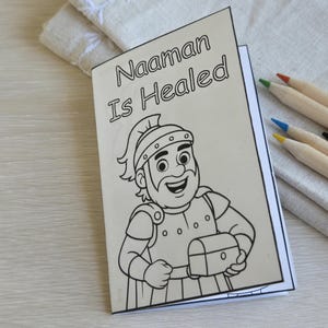 Può includere: Un libro da colorare in carta bianca con il testo nero Naaman Is Healed stampato sulla copertina. L'illustrazione raffigura un soldato dei cartoni animati che indossa un elmo e un'armatura, mentre tiene in mano un piccolo forziere.