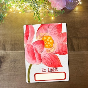 May include: A rectangular bookplate featuring a pink lotus flower watercolour illustration. The flower has a yellow centre and green stem. The words "EX LIBRIS" are printed below the flower, with a blank space for personalisation.