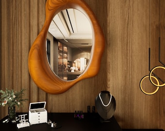 May include: A large, organically shaped wooden mirror hangs on a wood-paneled wall. The mirror reflects a room interior. Below, a black vanity displays jewelry, a jewelry box, and a necklace on a bust. Decorative lighting hangs from the ceiling.