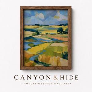 May include: A framed landscape painting featuring a vibrant scene of yellow fields, green meadows, and blue water under a cloudy sky. The artwork is enclosed in a dark brown wooden frame. Below the frame, the text reads CANYON & HIDE LUXURY WESTERN WALL ART.