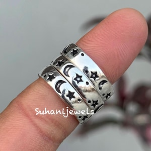 Può includere: Tre anelli d'argento impilati su un dito, ognuno con un motivo ripetuto di lune crescenti, stelle e punti. Gli anelli hanno una finitura lucida e sono incisi con il disegno. Il testo "Suhanijewels" è visibile sul dito.