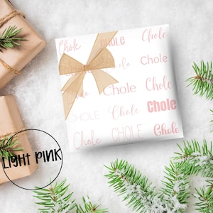 May include: White gift wrap with a repeating pattern of the word "Chole" in light pink. A light brown ribbon is tied on top. The words "LIGHT PINK" are in a black circle in the lower left corner.