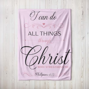 May include: A light pink blanket with the text "I can do all things through Christ who strengthens me" in black script. The blanket also features decorative flourishes and the scripture reference Philippians 4:13.