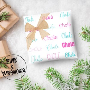 May include: White gift wrap with the word "Chole" in pink and turquoise script. A tan ribbon bow adorns the wrapped gift. The words "Pink & Turquoise" are in a black circle in the lower left corner. Green pine branches are in the background.