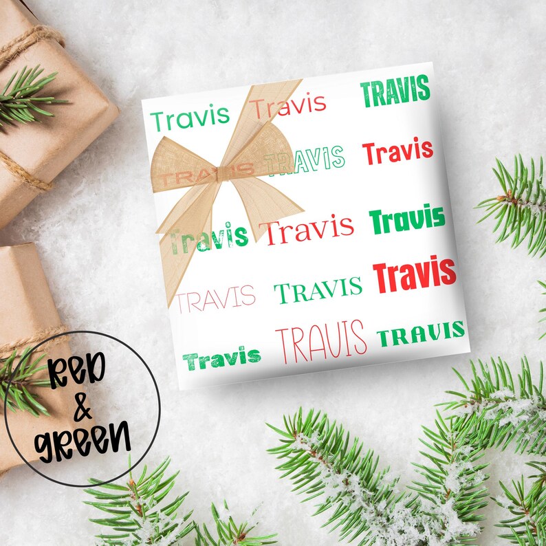 May include: White gift wrap with the name "Travis" repeated in red and green. A tan bow adorns the wrapped gift. The words "Red & Green" are in a circle in the lower left corner. Evergreen branches are in the background.