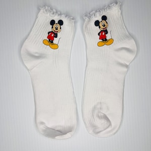 以下が含まれることがあります： クリーム色の斑点のある釉薬が施された、3つのセラミックマグのセット。各マグには、青、緑、黄色の色合いの手描きの花柄が施されています。マグはシンプルで丸みを帯びた形状で、持ちやすいハンドルが付いています。