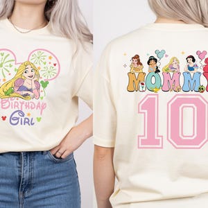 Puede incluir: Camiseta color crema con un gr&aacute;fico de Rapunzel y el texto "Birthday Girl" en la parte delantera. La parte trasera de la camiseta muestra la palabra "Mommy" con ilustraciones de princesas y el n&uacute;mero "10" en rosa.