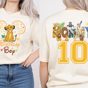 Puede incluir: Camiseta color crema con un dise&ntilde;o de Simba, orejas de Mickey Mouse y el texto "Birthday Boy". La parte trasera muestra "HONEY" con personajes de El Rey Le&oacute;n y el n&uacute;mero "10" en amarillo. Un dise&ntilde;o divertido y tem&aacute;tico.