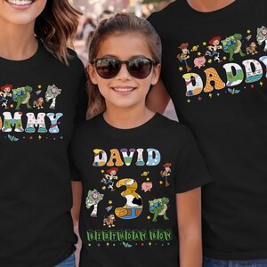 May include: Black t-shirts with colorful graphics featuring characters and text from the movie Toy Story. The shirts say "Mommy", "Daddy", and "David 3 Birthday Boy". The shirts are for a family.