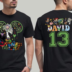 May include: Black t-shirt featuring Buzz Lightyear and Disney Trip 2.26 graphics on the front. The back displays Toy Story characters, the name "DAVID", and the number "13" in green.