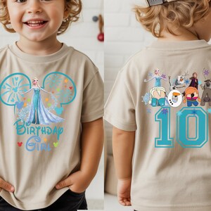 Puede incluir: Camiseta beige de manga corta con un dise&ntilde;o de Elsa de Frozen y el texto "Birthday Girl". La parte trasera de la camiseta muestra el n&uacute;mero "10" en azul, junto con otros personajes de Frozen.