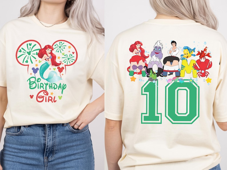 Puede incluir: Camiseta color crema con un gr&aacute;fico colorido de Ariel de La Sirenita, fuegos artificiales y el texto "Birthday Girl". La parte posterior de la camiseta muestra varios personajes y el n&uacute;mero "10" en verde.