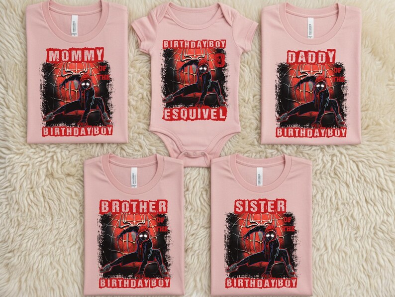 Puede incluir: Un conjunto de camisetas rosas y un body con un gr&aacute;fico de superh&eacute;roe. Las camisetas llevan las etiquetas "Mam&aacute;", "Pap&aacute;", "Hermano" y "Hermana", con el texto "Birthday Boy". El body dice "Birthday Boy" y un nombre.