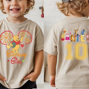 Puede incluir: Camiseta beige de manga corta con un dise&ntilde;o de Winnie the Pooh. La parte delantera presenta un gr&aacute;fico con el texto "Birthday Girl". La parte trasera muestra el nombre "Daniel" y el n&uacute;mero "10", junto con otros personajes.