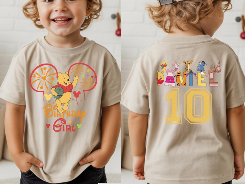 Puede incluir: Camiseta beige de manga corta con un dise&ntilde;o de Winnie the Pooh. La parte delantera presenta un gr&aacute;fico con el texto "Birthday Girl". La parte trasera muestra el nombre "Daniel" y el n&uacute;mero "10", junto con otros personajes.