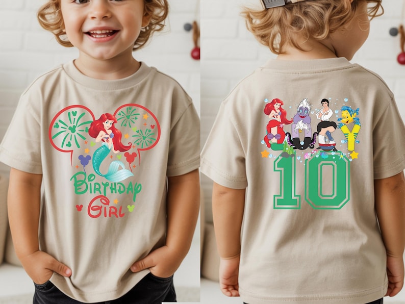 Puede incluir: Camiseta beige de manga corta con un gr&aacute;fico colorido de Ariel la sirenita, fuegos artificiales y el texto "Birthday Girl". La parte trasera de la camiseta muestra el n&uacute;mero "10" y otros personajes de la pel&iacute;cula La Sirenita.