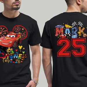May include: Black t-shirt featuring a red Lightning McQueen car graphic with the text "Disney Trip 26" on the front. The back of the shirt displays the name "MARK" and the number "25" in red.